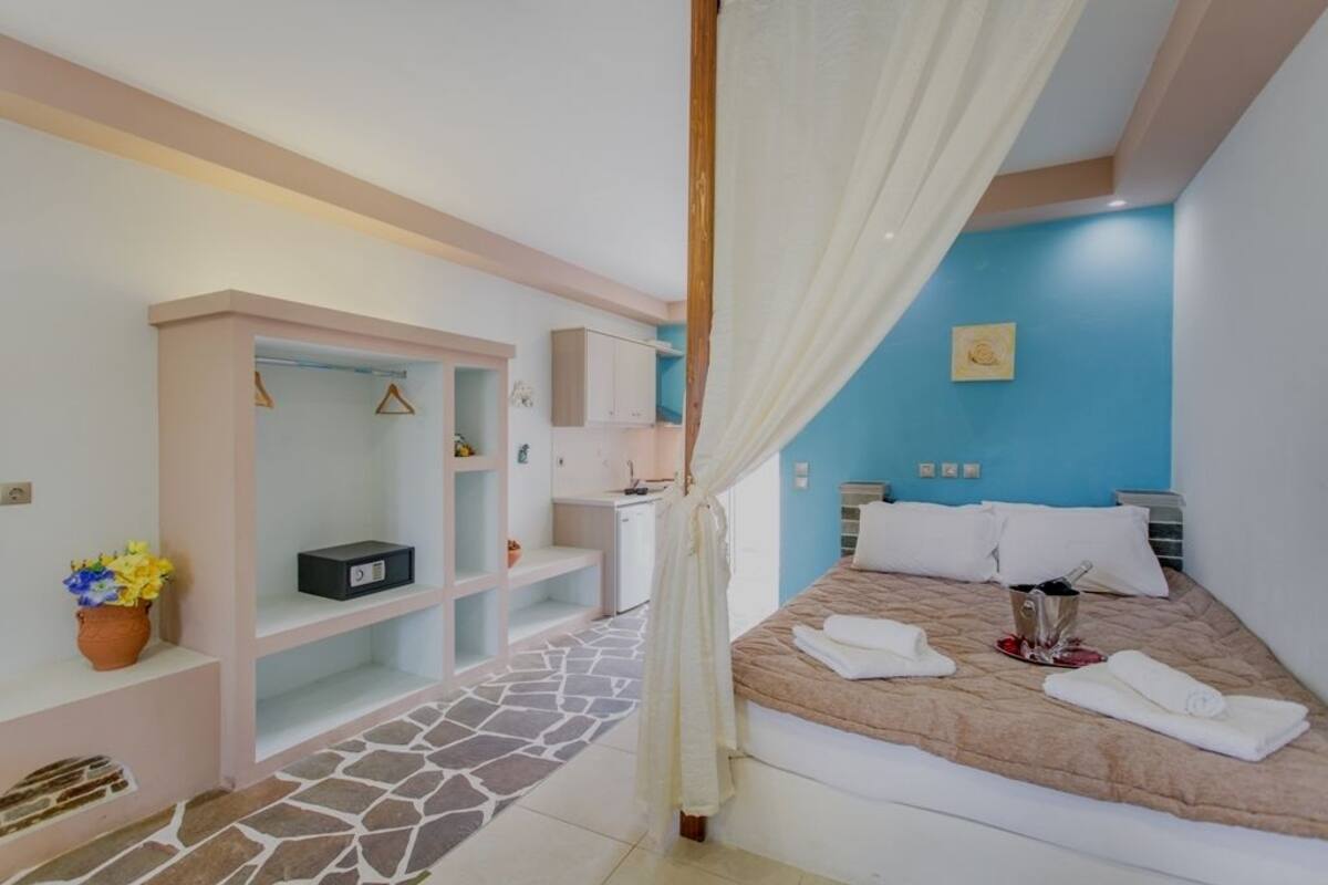 A bedroom with a bed, a bedside table, a nightstand, a wardrobe, a mirror, and a window.