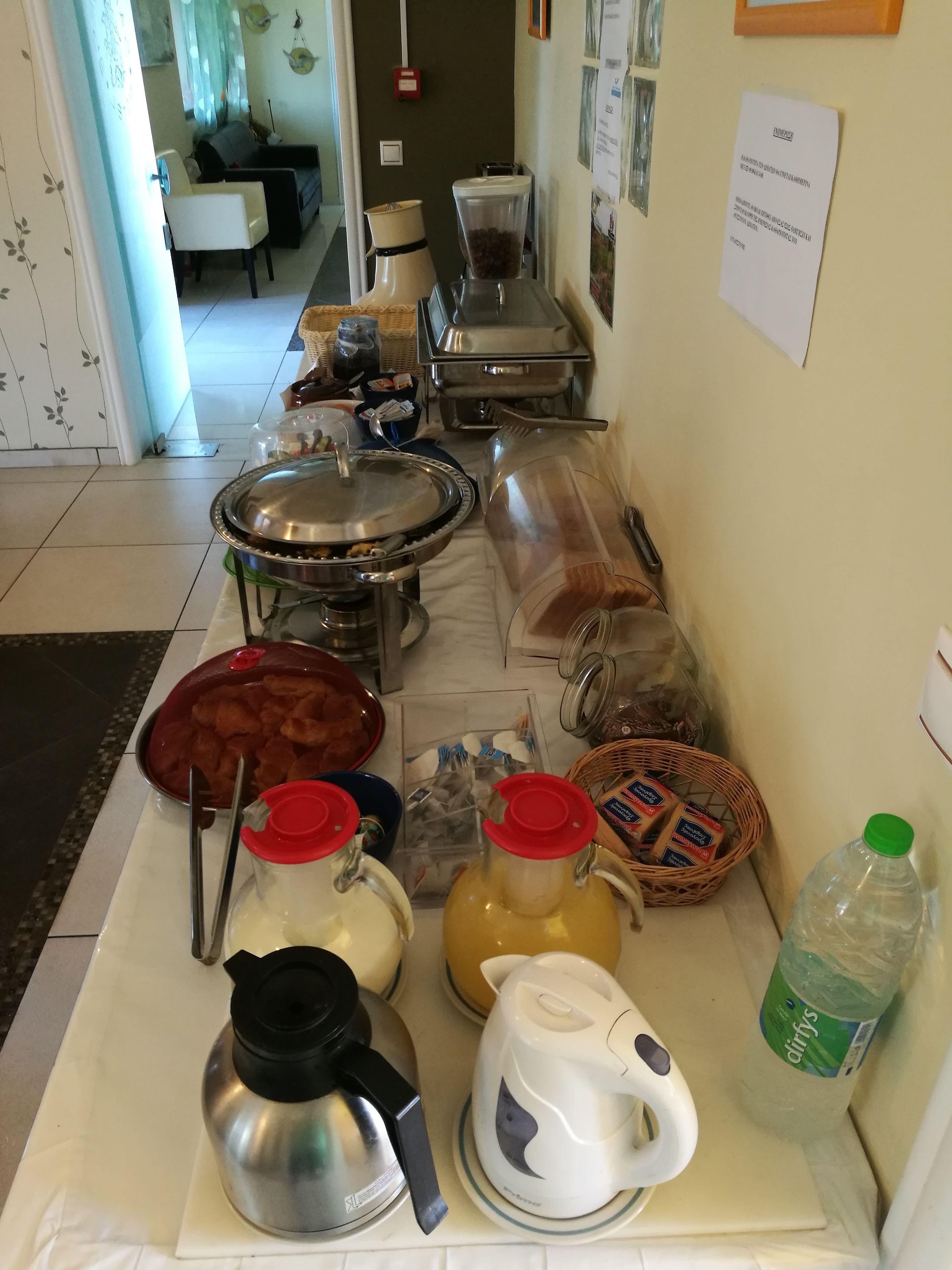 A buffet setup with various food items, a coffee machine, and a water dispenser.