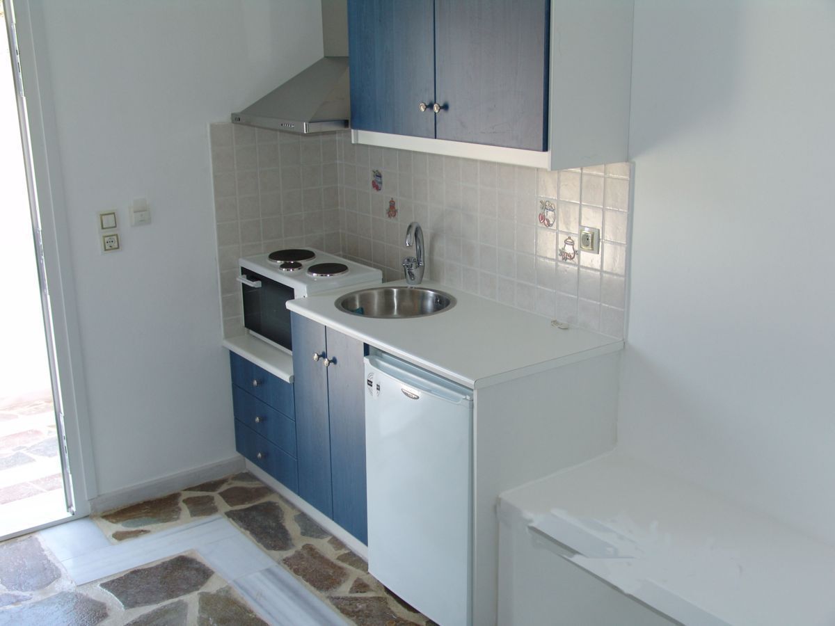 A compact kitchen with a built-in stove, sink, and a small refrigerator.
