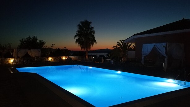 Una piscina al crepuscolo con un tramonto sullo sfondo.