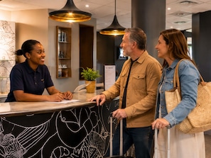 A reception desk with a black and white abstract design, a potted plant, and a menu board in a modern lobby with pendant lighting. - ibis budget Orly Chevilly Tram 7 (Chevilly-Larue)