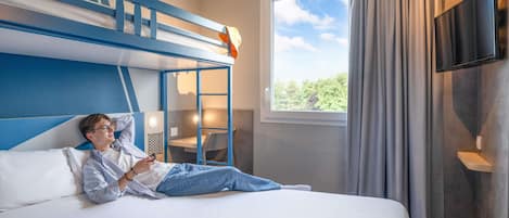 A hotel room with a bunk bed, a desk, a chair, a TV, and a tennis racket on the bed.