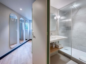 Une salle de bain moderne avec une douche, un lavabo et un miroir.