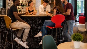 Zona de bar con mostrador, taburetes y una variedad de botellas en estanterías.