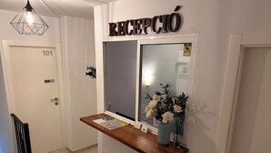 A reception desk with a wooden counter, a mirror, and a vase with flowers. - Hostal del Mar (Tossa de Mar)
