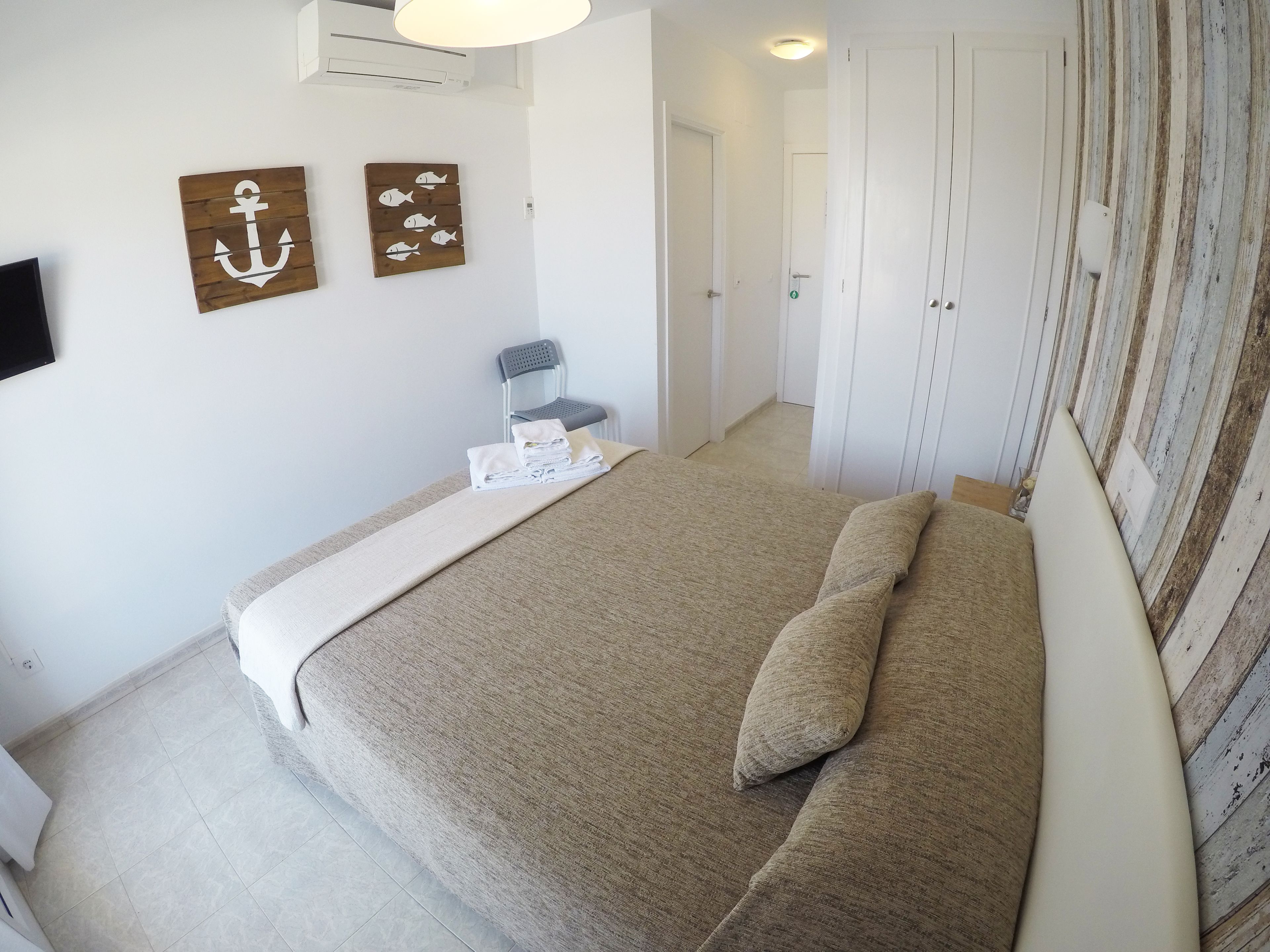 Een slaapkamer met een bed, een stoel en kunst aan de muur.