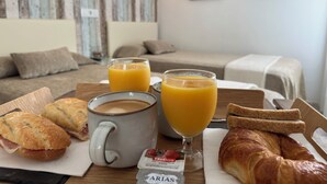 A breakfast tray with croissants, a coffee mug, juice, and a croissant sandwich. - Hostal del Mar (Tossa de Mar)