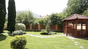 Un jardín bien cuidado con un pabellón, setos recortados y un camino de piedra.