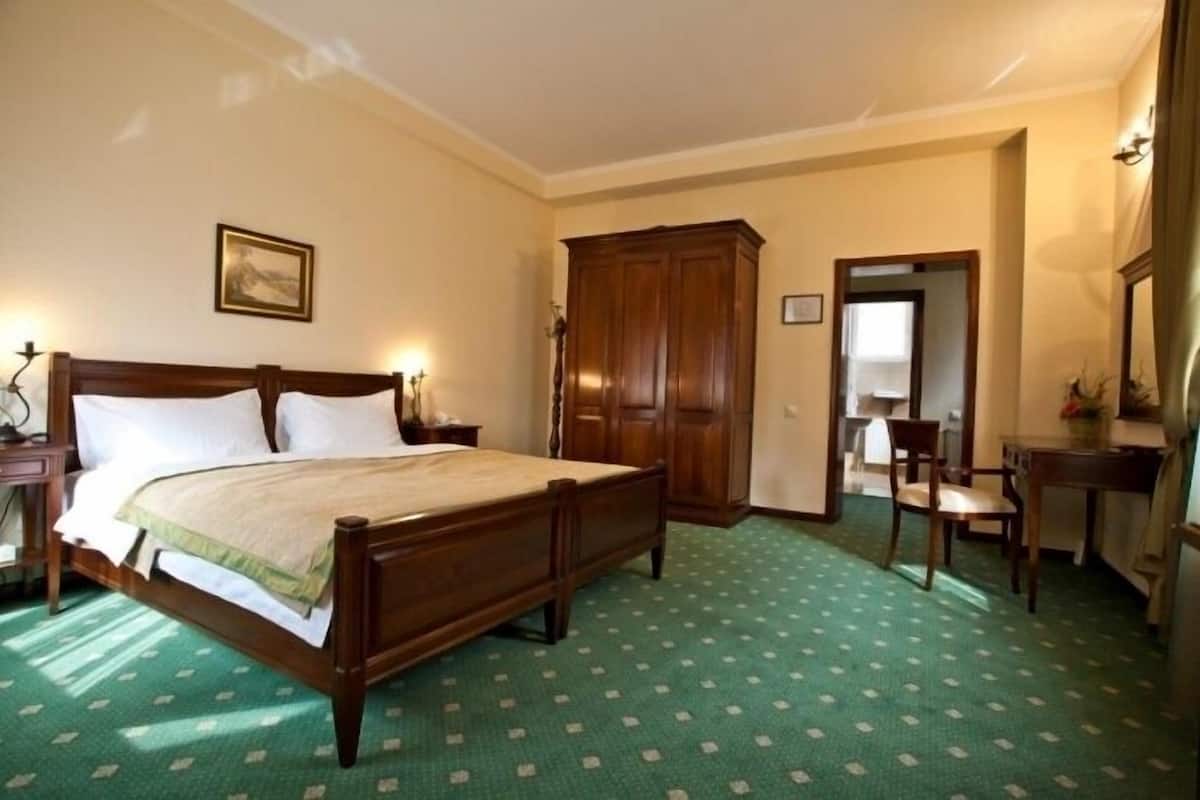 Een slaapkamer met een houten bed, een bureau en een stoel.