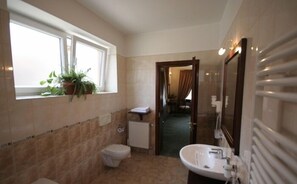 A bathroom with a toilet, sink, and window with plants.