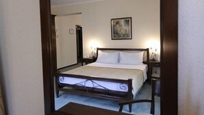 Un dormitorio con un espejo grande, una cama, una mesita de noche y un cuadro colgado en la pared.
