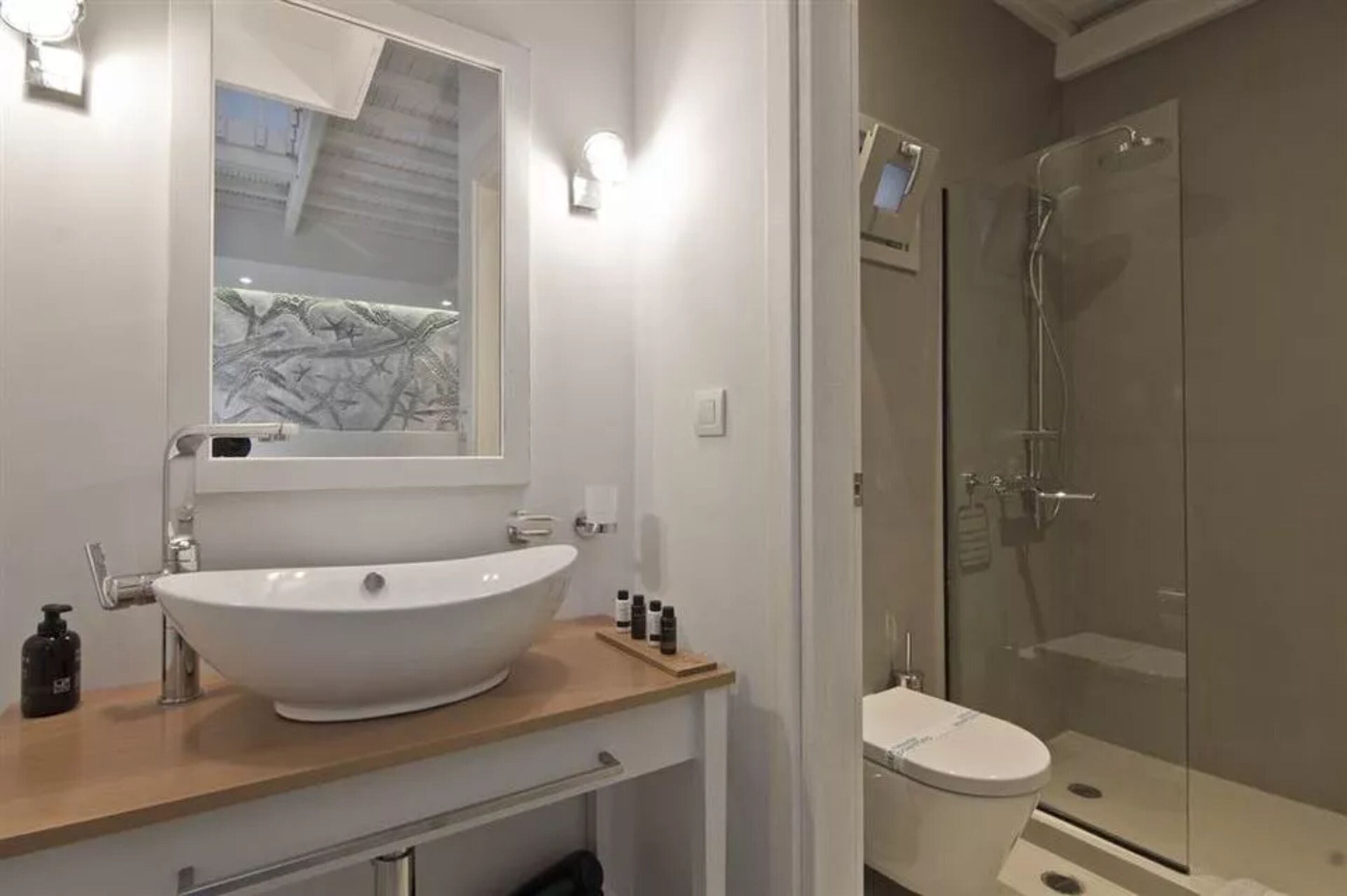 A modern bathroom with a large white sink, a glass shower enclosure, and a toilet.