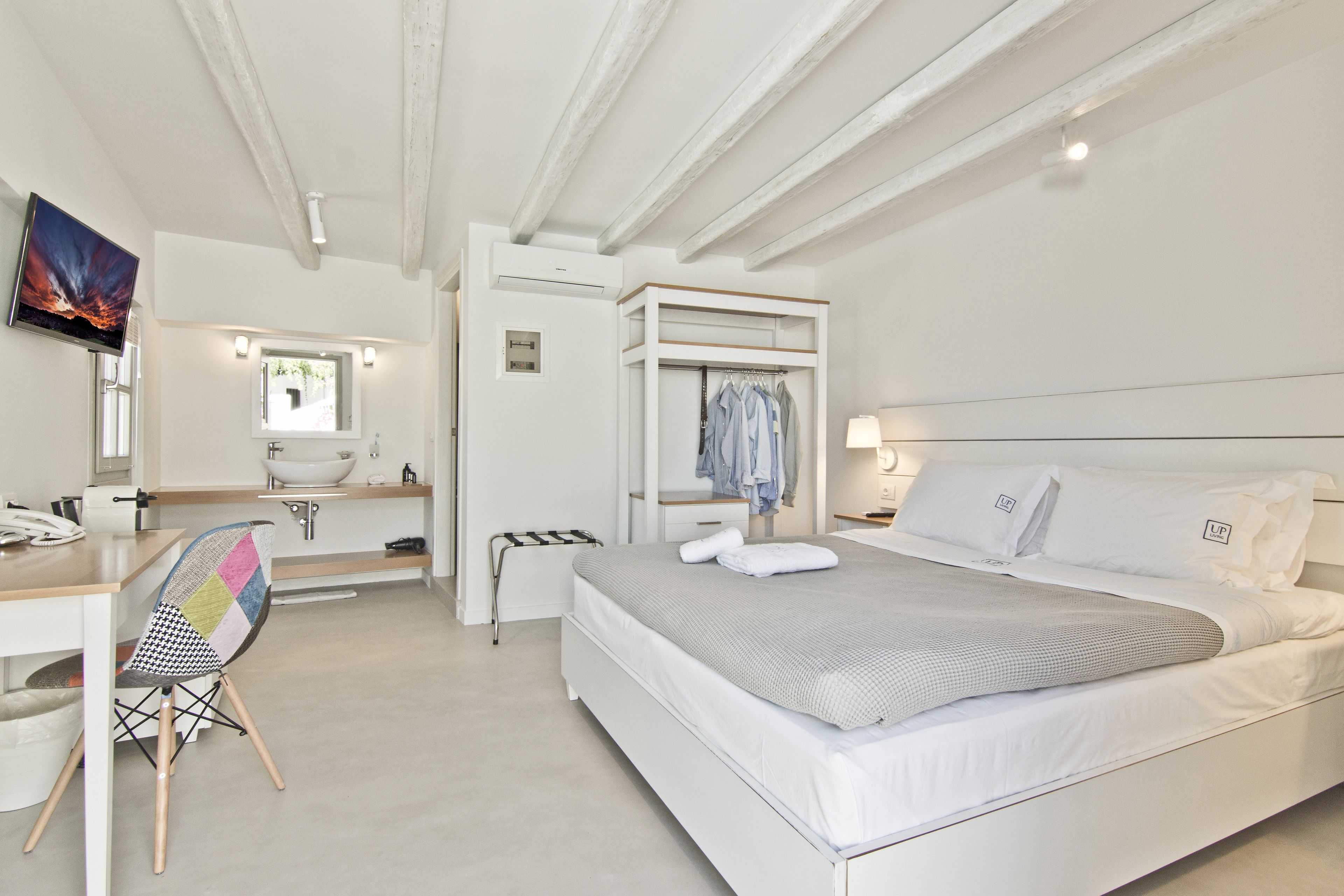 Una camera da letto moderna con un letto, una scrivania, una sedia, una TV e un bagno.