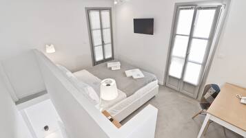 A modern, well-lit bedroom with a bed, bedside lamps, and a desk.