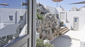 A modern building with white walls, a stone rock formation, and a staircase leading to a door. - Lindos Comfy Suites (Rhodes)