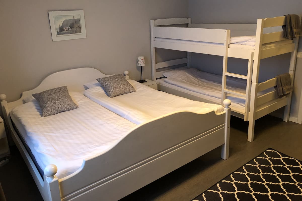 A bunk bed with two levels, a bedside table with a lamp, and a framed picture on the wall.