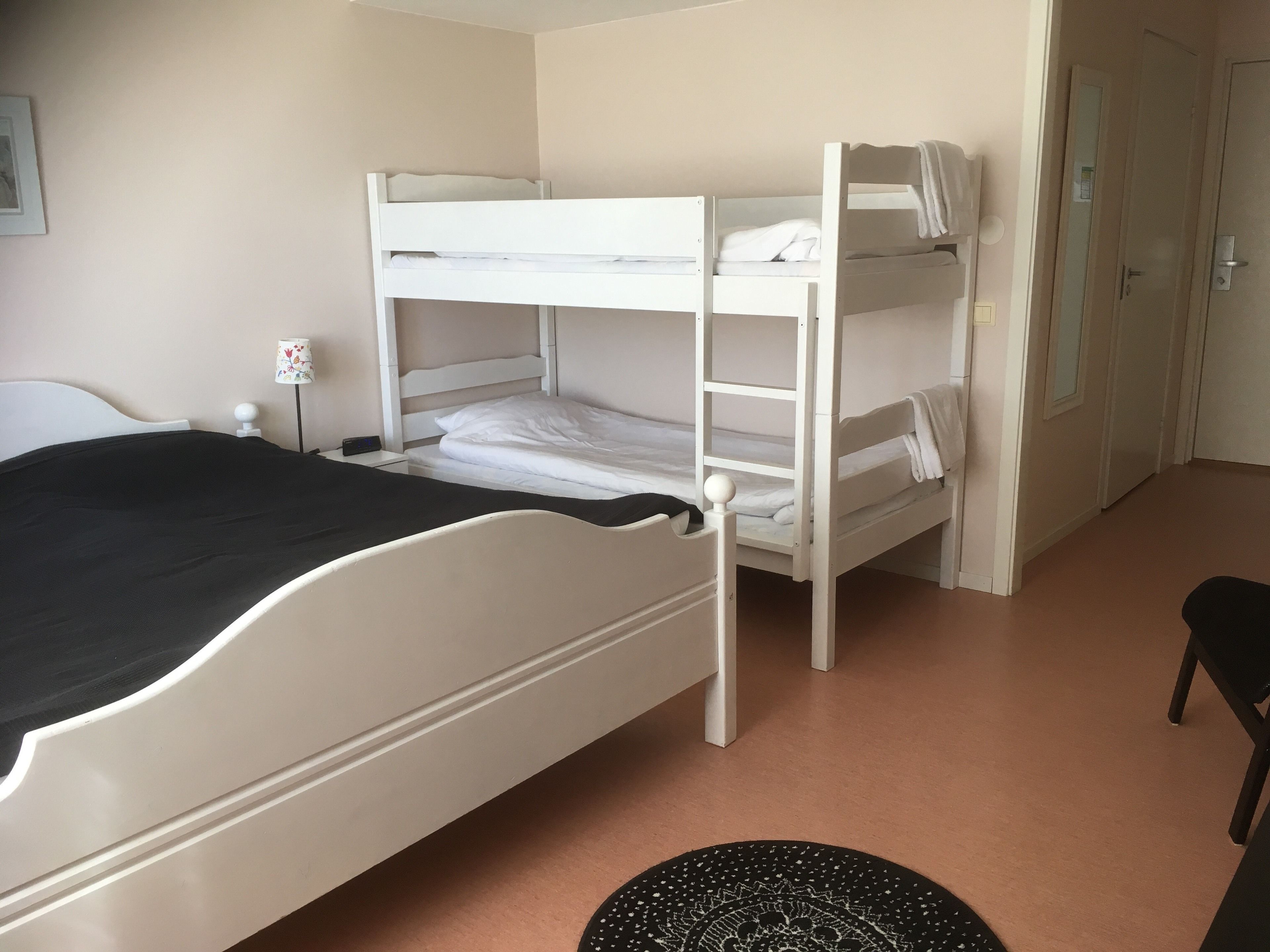 A bunk bed room with a single bed and a desk.