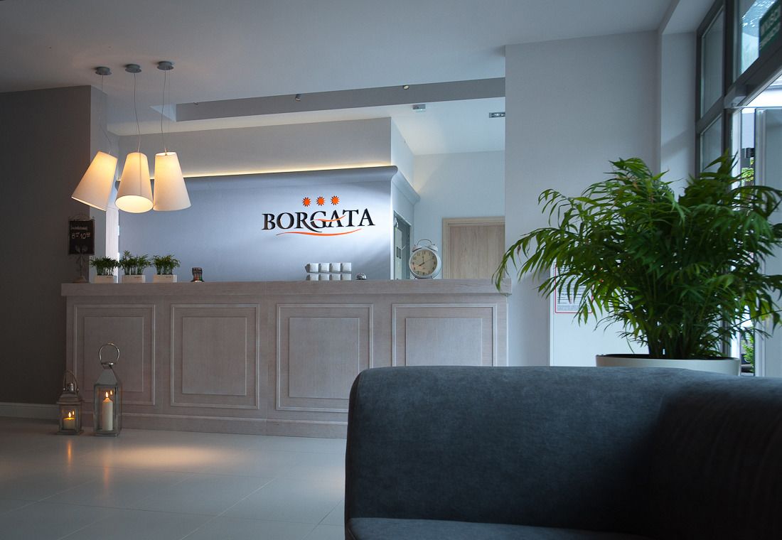 A reception area with a light-colored reception desk, a clock, and a potted plant.
