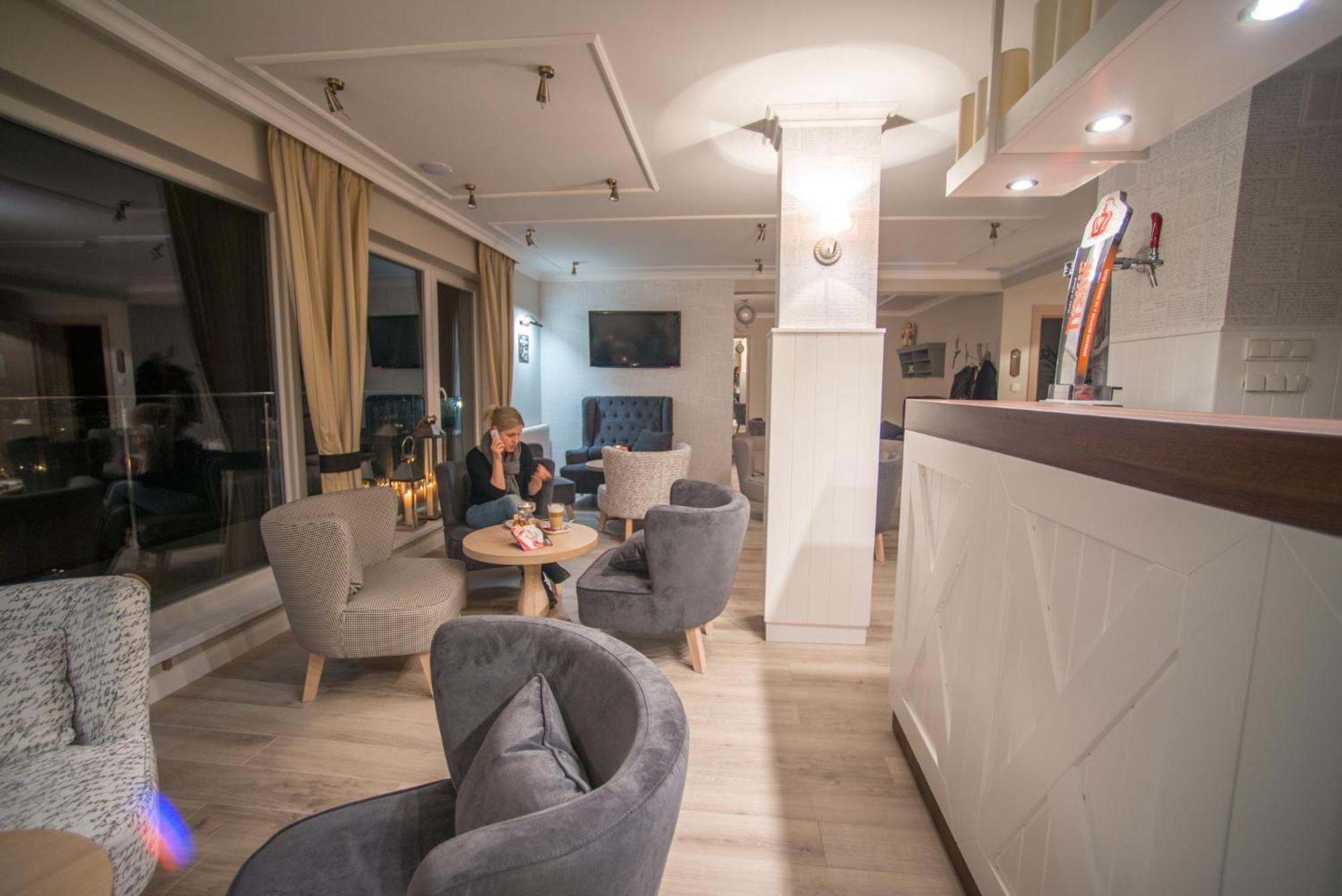Un moderno vestíbulo de hotel con zona de bar, asientos y una pantalla de televisión.