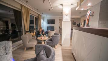 Un moderno vestíbulo de hotel con zona de bar, asientos y una pantalla de televisión.