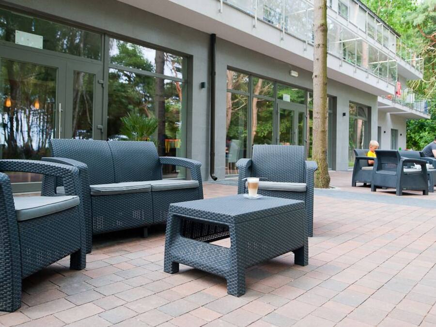 Outdoor seating with wicker furniture and a glass building in the background.