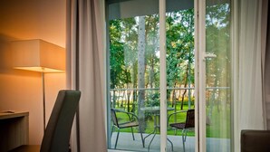 Una habitación con un gran ventanal corredero que da a un patio exterior con sillas y una mesa.