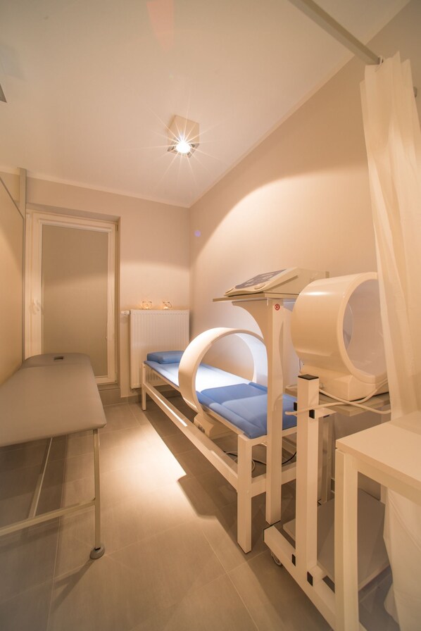 Un cuarto de tratamientos con dos camillas de terapia y una mesa de masaje.