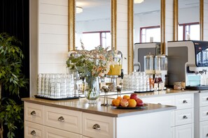 A breakfast bar with a fruit bowl, a vase with flowers, and a coffee machine. - Hotell Vesterhavet (Falkenberg)