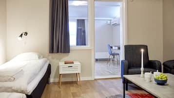 Quarto de hotel com cama, mesinha de cabeceira, escrivaninha, mesa com uma vela e vista para a varanda.
