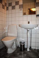 Un baño con inodoro, lavamanos y cubo de basura.