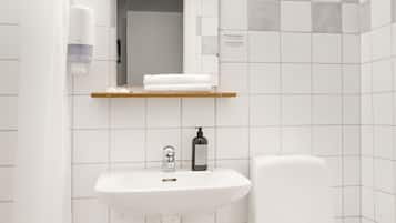 Une salle de bain avec un lavabo blanc, des toilettes et un rideau de douche.