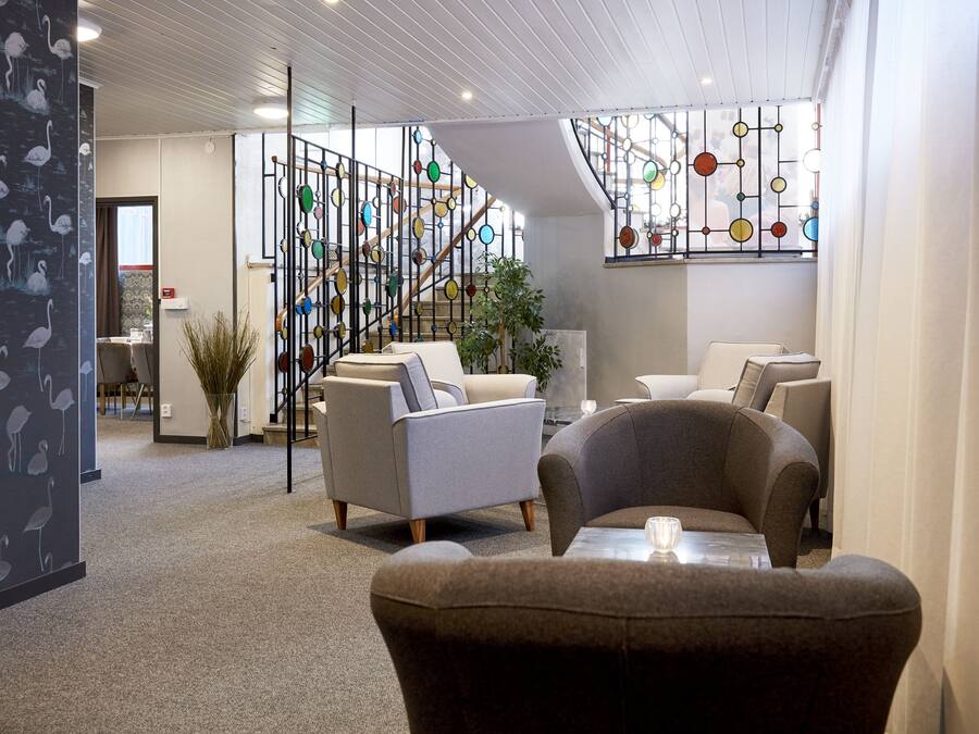 Un interior moderno con una escalera, una zona de estar y un muro decorativo.