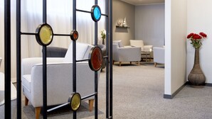 Un salon moderne avec un canapé, des fauteuils et une cloison décorative en métal.