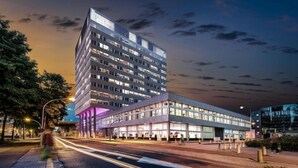 Un hotel moderno de varios pisos, con un edificio destacado en esquina y un cuerpo anexo de techo plano.