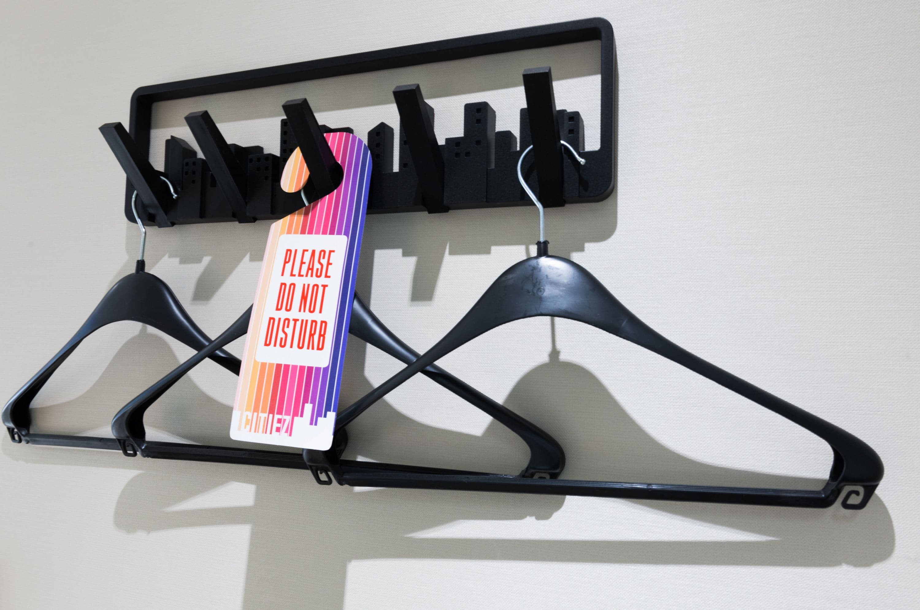 A wall-mounted coat rack with multiple hooks and a sign that reads "PLEASE DO NOT DISTURB."