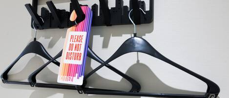 A wall-mounted coat rack with multiple hooks and a sign that reads "PLEASE DO NOT DISTURB."