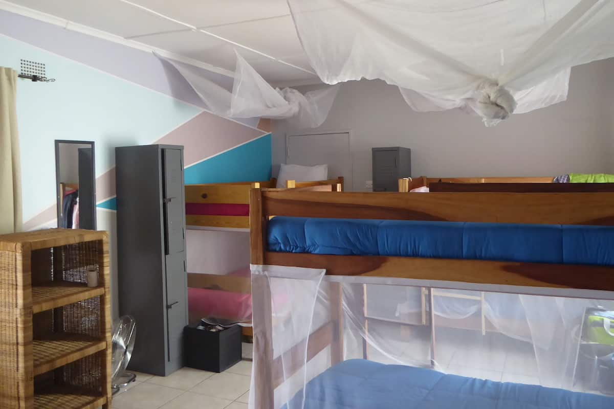 Une chambre de dortoir équipée de lits superposés, d’une armoire, d’un miroir, d’un ventilateur et d’une étagère.