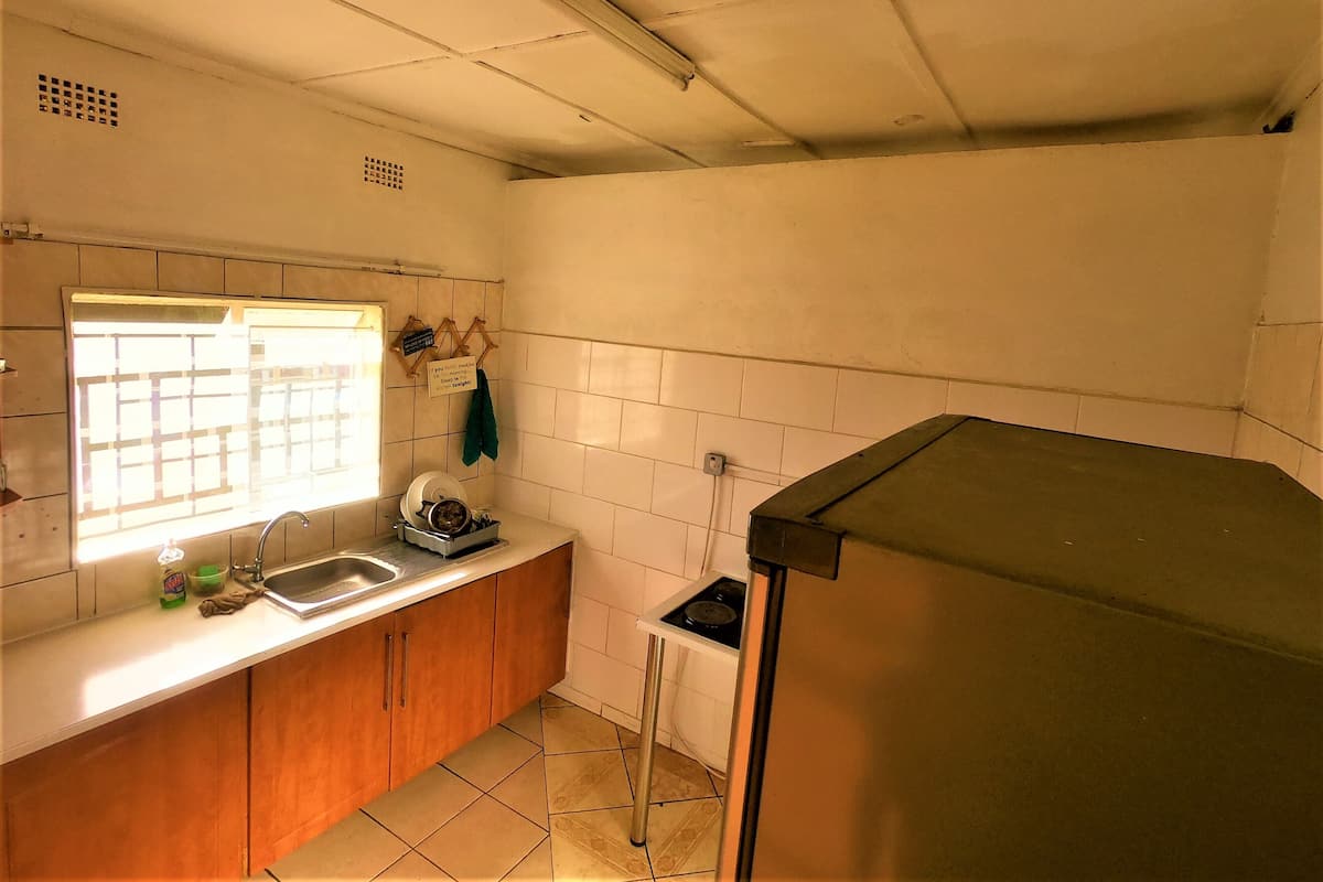 Une cuisine de taille réduite, équipée d’un évier, d’une fenêtre et d’une petite cuisinière.