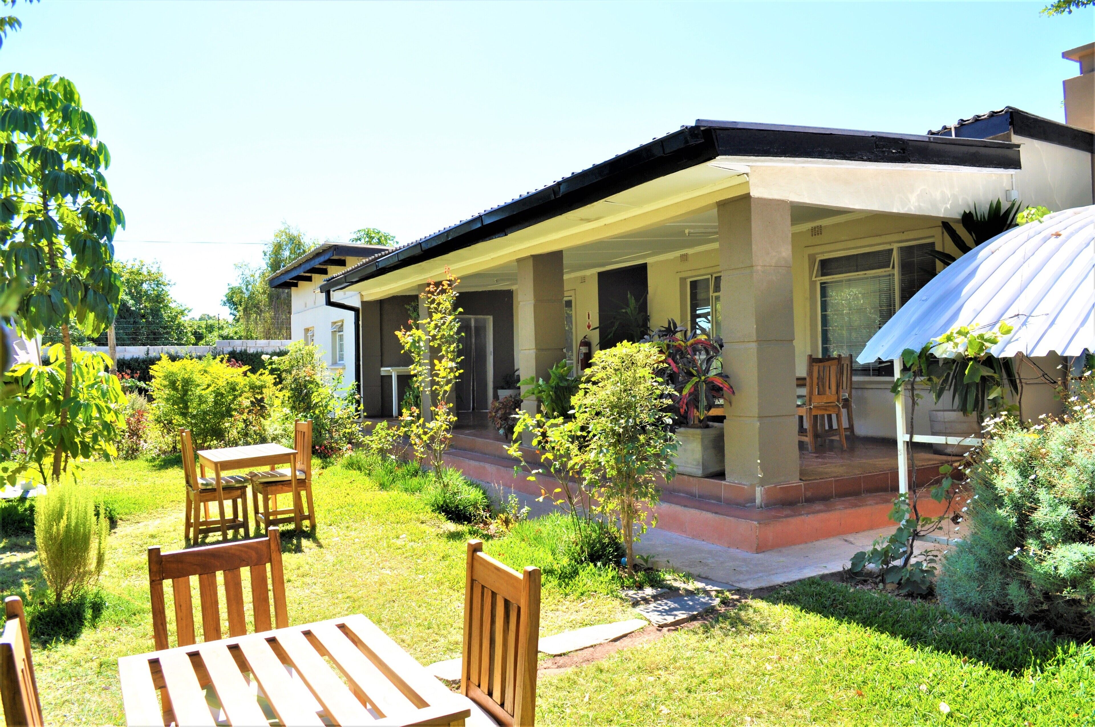 Ein Haus mit überdachter Veranda, Rasen und Garten.