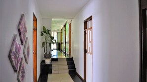 Ein Flur mit Treppe, Blumentopf und einer Tür mit Hausnummer.