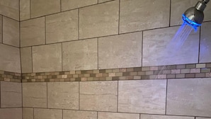 A shower with beige tiles and a blue water stream. - Delux Inn Clearwater (Clearwater)
