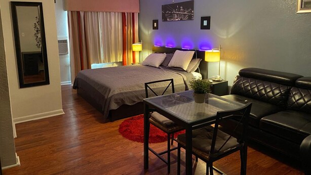 A modern bedroom with a bed, a desk, a chair, a sofa, and a ceiling fan. - Delux Inn Clearwater (Clearwater)