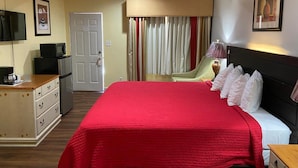 A hotel room with a large bed, a desk with a computer, a chair, and a television. - Delux Inn Clearwater (Clearwater)