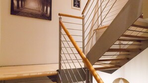 Eine Treppe mit hölzernem Geländer und Metallspindeln, ein gerahmtes Bild an der Wand und ein kleines Schild über dem Geländer.
