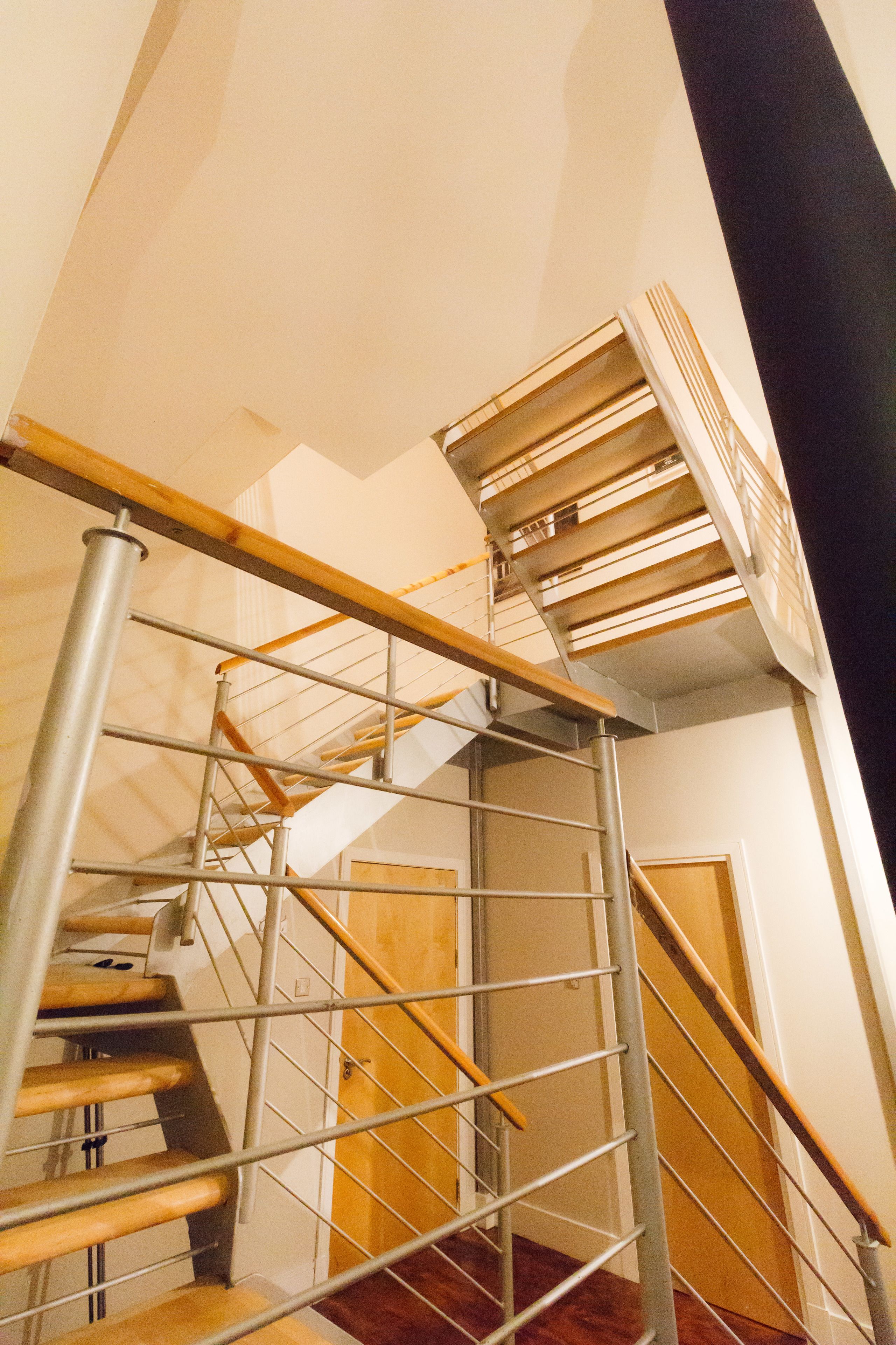 A spiral staircase with metal railings and wooden steps, leading to an upper floor.