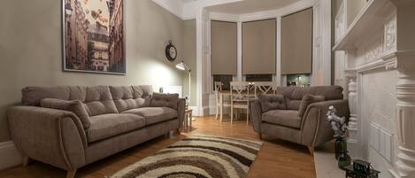 A living room with two sofas, a rug, and a fireplace.