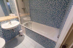 Ein Badezimmer mit einem weißen Waschbecken, einer gläsernen Dusche und blauen Mosaikfliesen an den Wänden.