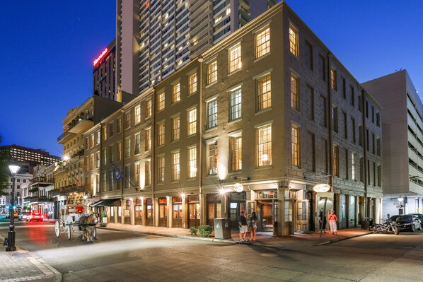 A historic building with multiple stories, large windows, and a ground-level entrance with a sign. - La Galerie French Quarter Hotel (New Orleans)