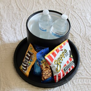 A black tray with two bottles of water, a bag of peanut butter, a bag of plant-based snacks, and a bag of Zapp's potato chips. - La Galerie French Quarter Hotel (New Orleans)