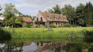 A large house with a pond in front, surrounded by trees and a grassy lawn. - 't Vijverhof (Geraardsbergen)